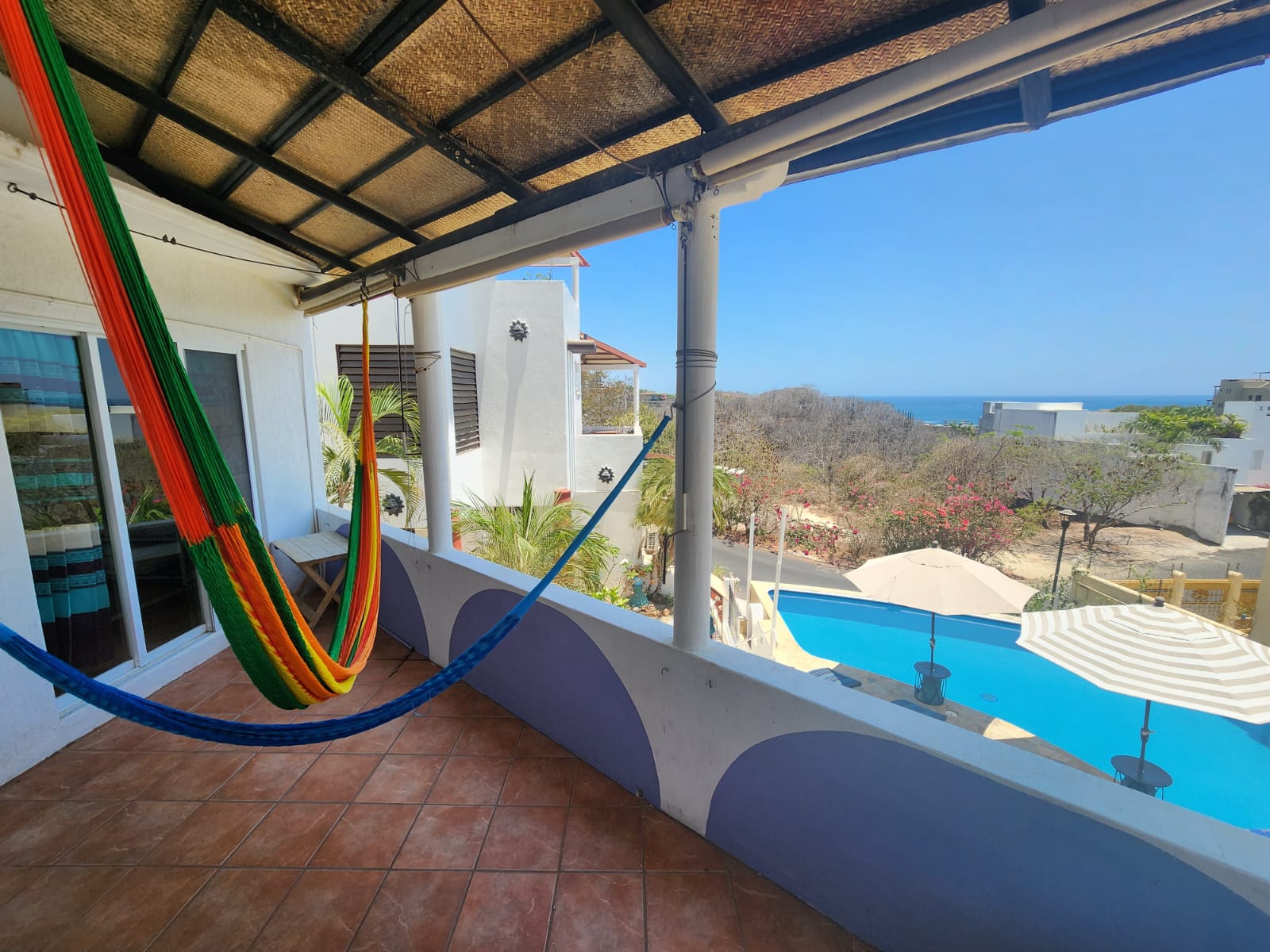 Daytime pool and ocean view from balcony, hammocks